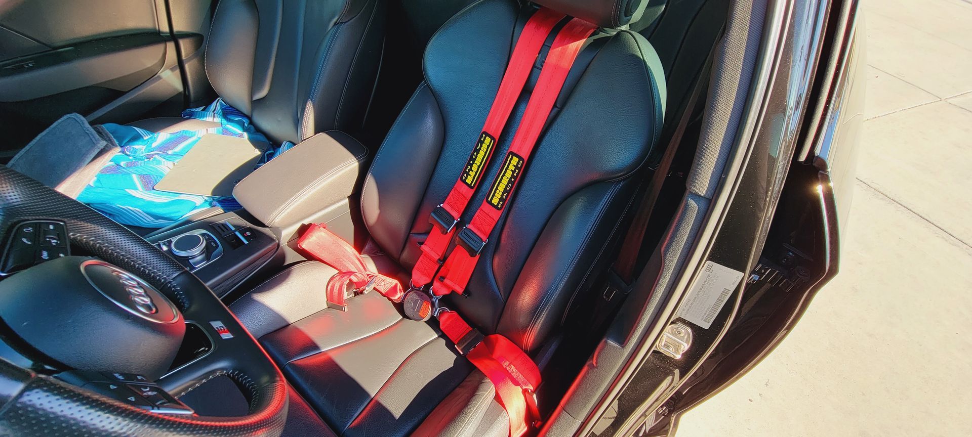 A close up of a car seat with a red seat belt | Griffin Motorwerke