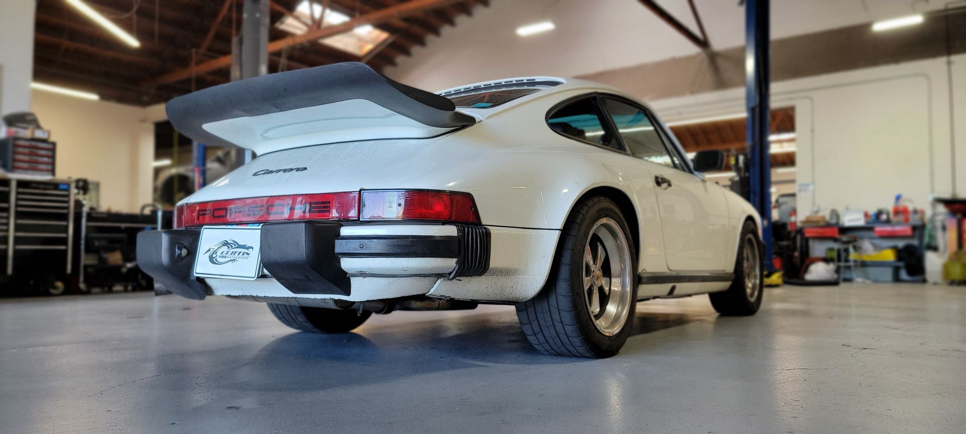 A white porsche 911 turbo is parked in a garage | Griffin Motorwerke