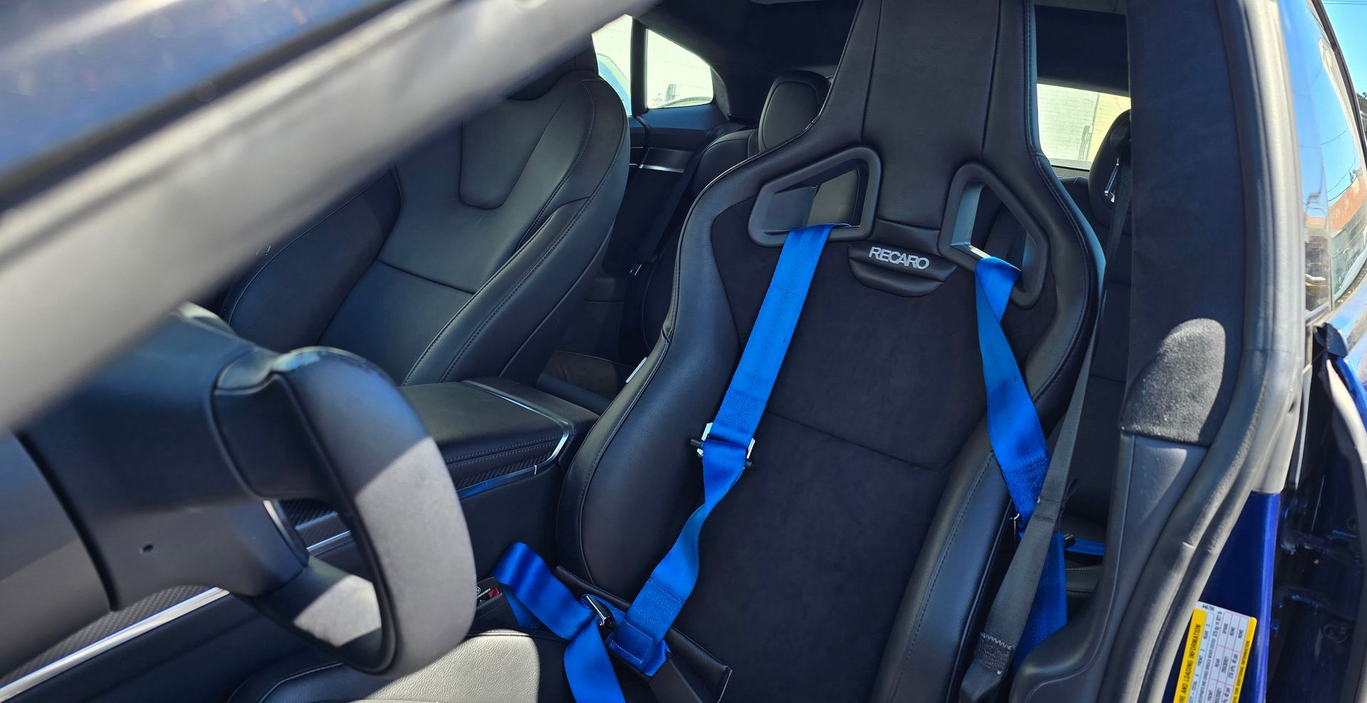 A black car with blue seat belts on the seats | Griffin Motorwerke