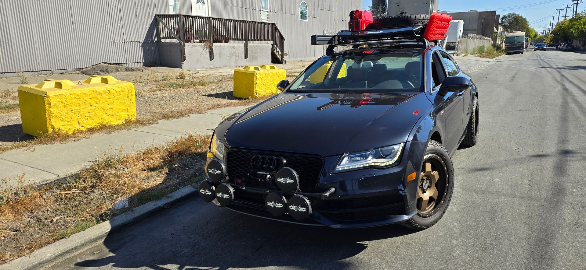 A black car with a roof rack is parked on the side of the road | Griffin Motorwerke