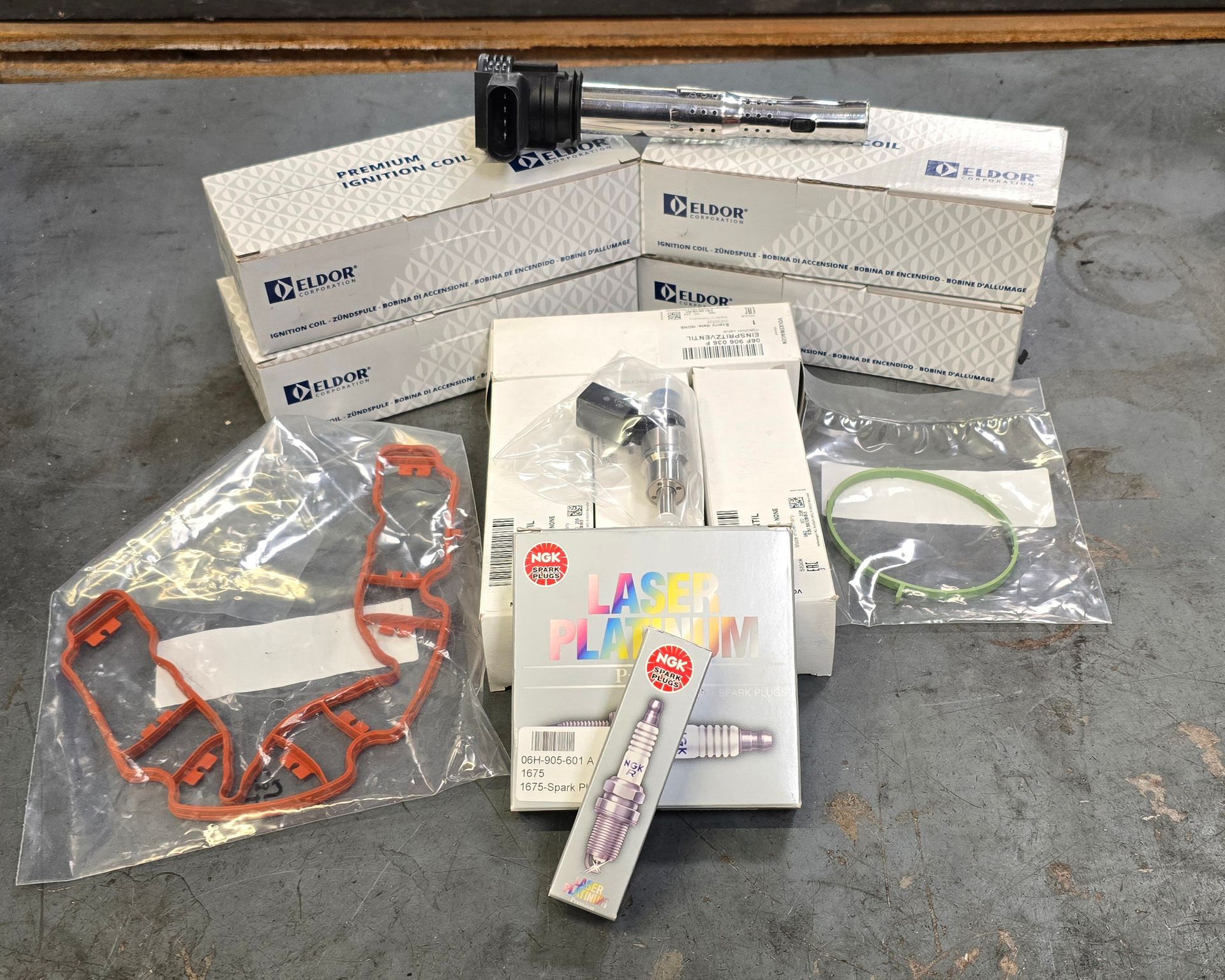New ignition coils, spark plugs, and gaskets prepared for service on a 2012 Volkswagen Golf R.