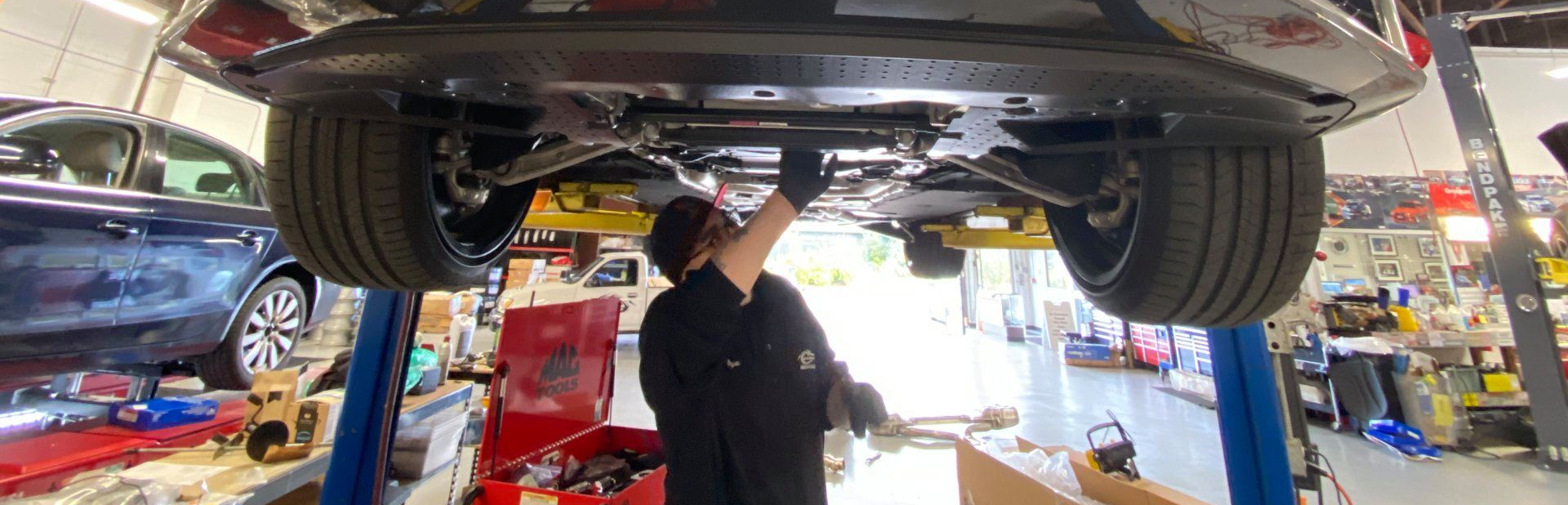 A man is working under a car on a lift in a garage | Griffin Motorwerke