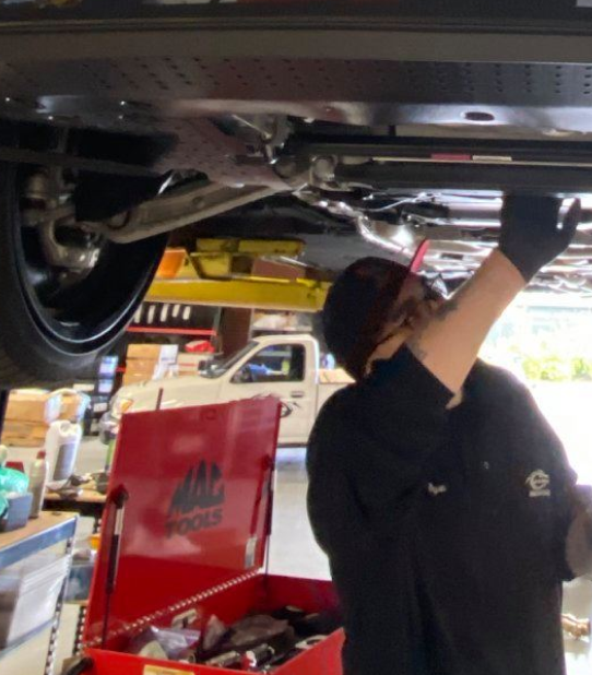 A man is working under a car in a garage | Griffin Motorwerke