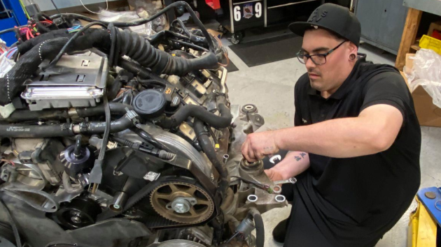 A man is working on a car engine in a garage | Griffin Motorwerke