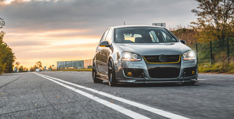 A silver car is driving down a road at sunset | Griffin Motorwerke