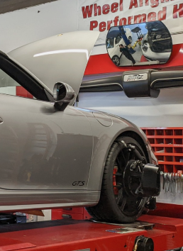 A car with the hood up is on a wheel alignment machine | Griffin Motorwerke