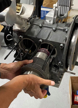 A person is holding a piece of metal in front of a engine | Griffin Motorwerke