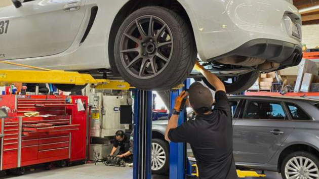 A man is working on a car on a lift in a garage | Griffin Motorwerke