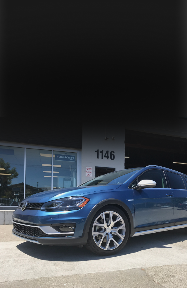 A blue volkswagen golf is parked in front of a car dealership | Griffin Motorwerke