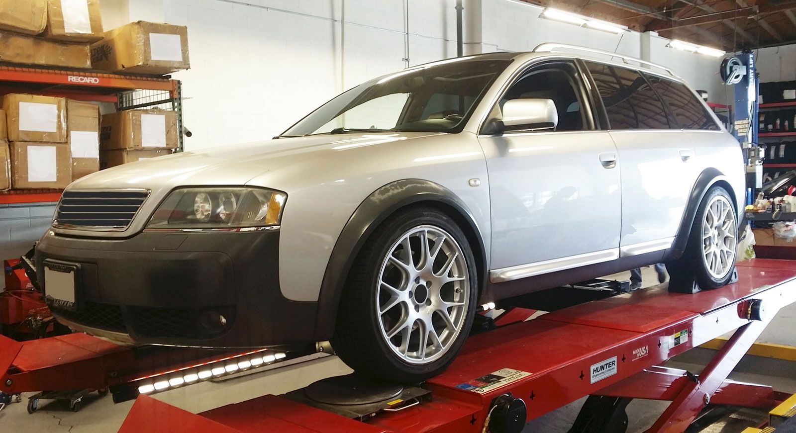 A silver car is sitting on a red lift in a garage | Griffin Motorwerke