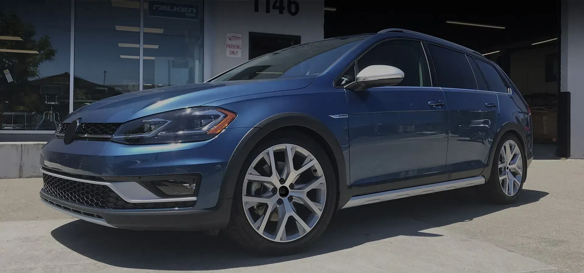 A blue volkswagen golf is parked in front of a car dealership | Griffin Motorwerke