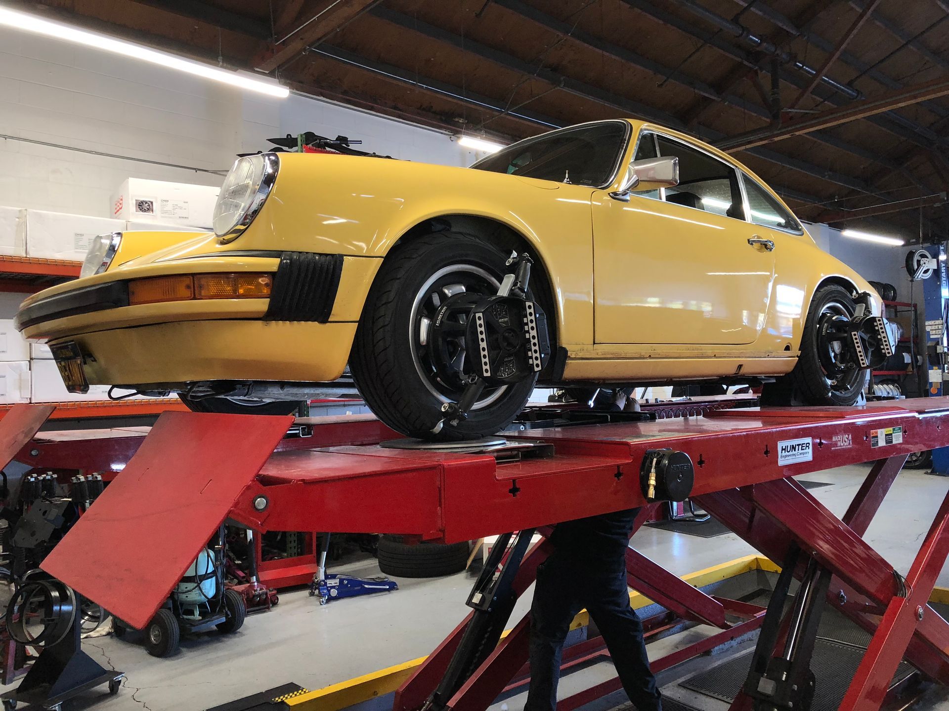 A yellow porsche is sitting on top of a red lift in a garage | Griffin Motorwerke