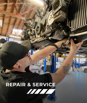 A man is working on the underside of a car in a garage | Griffin Motorwerke