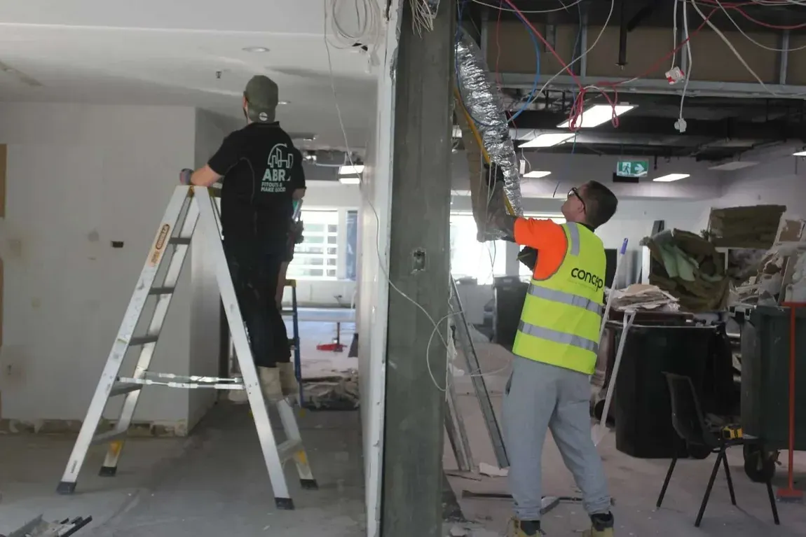 A man in a yellow vest is standing on a ladder
