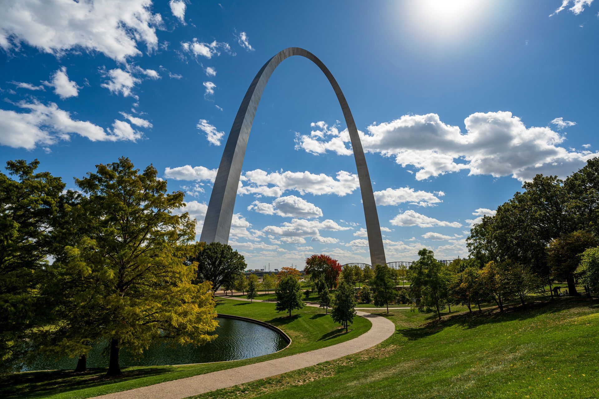 The gateway arch is surrounded by trees and a path in a park.