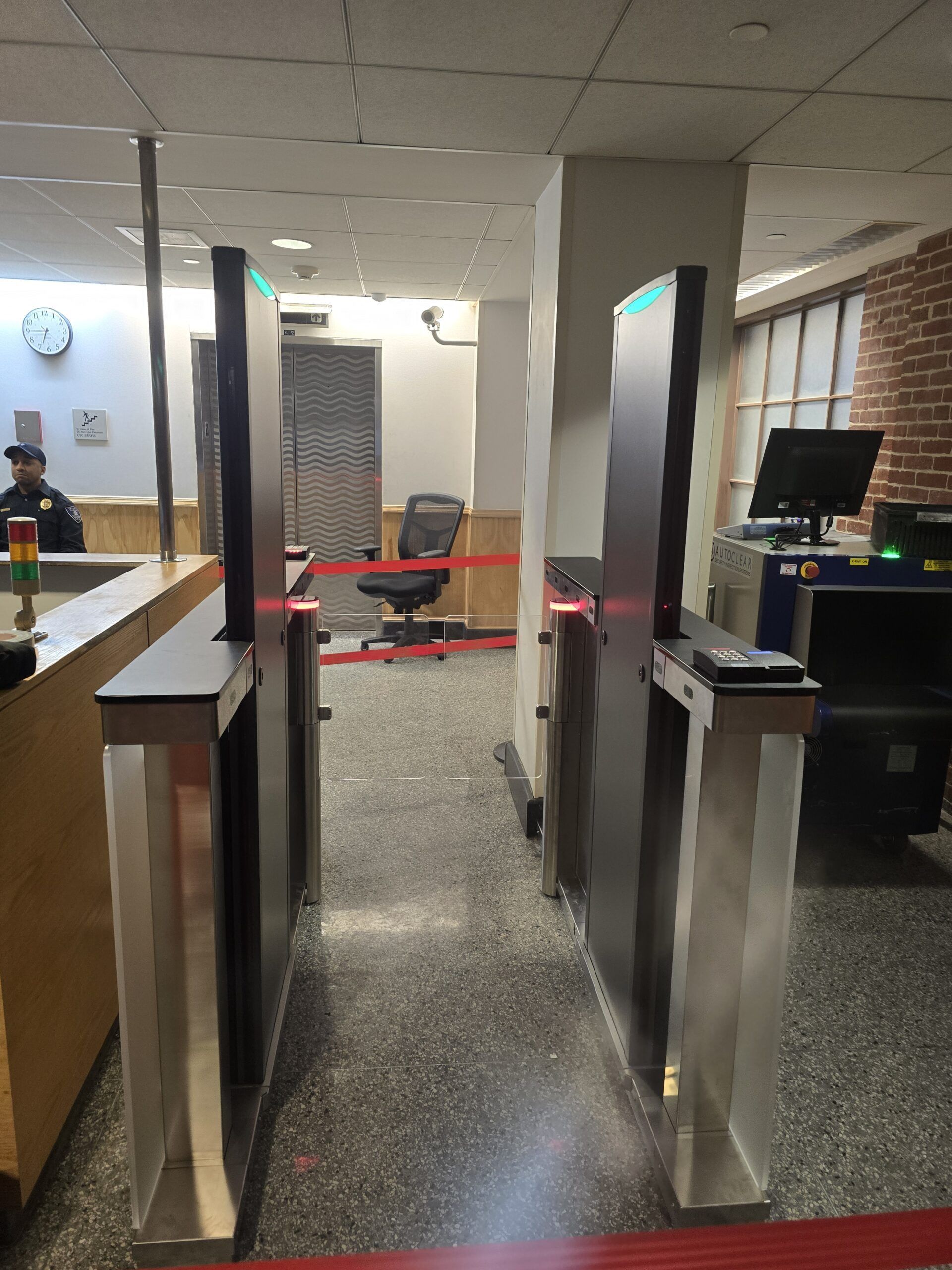 Security entrance with metal detectors; red barrier tape.