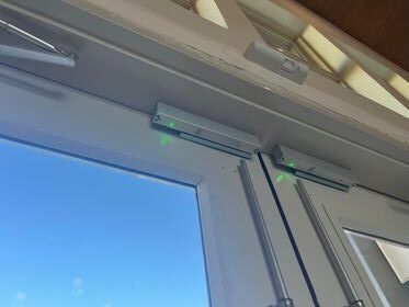 White door with green lights, likely security sensors, against a blue sky.