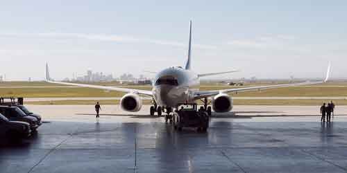 A passenger jet on the tarmac of an airport, with a city skyline in the background.