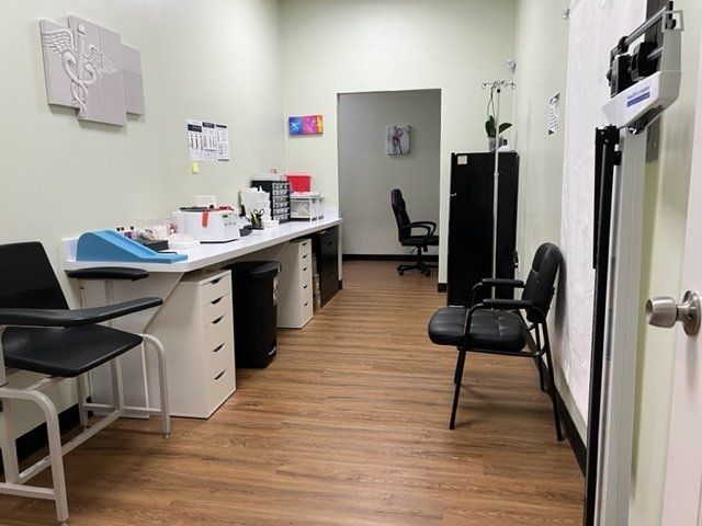 A doctor 's office with a desk , chairs , and a scale.