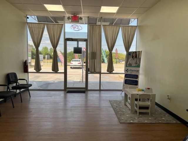 A waiting room with a table and chairs in front of a large window.