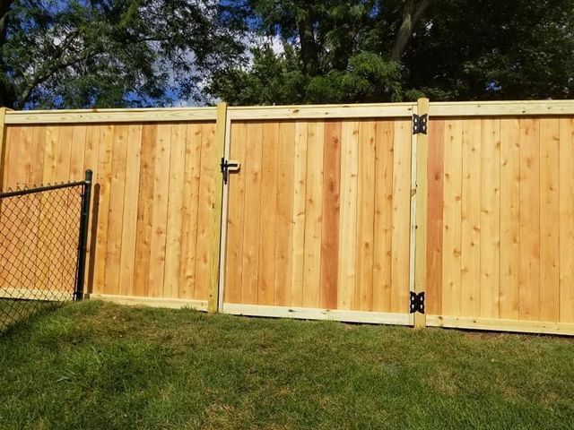 A wood privacy fence with a chain link fence behind it.