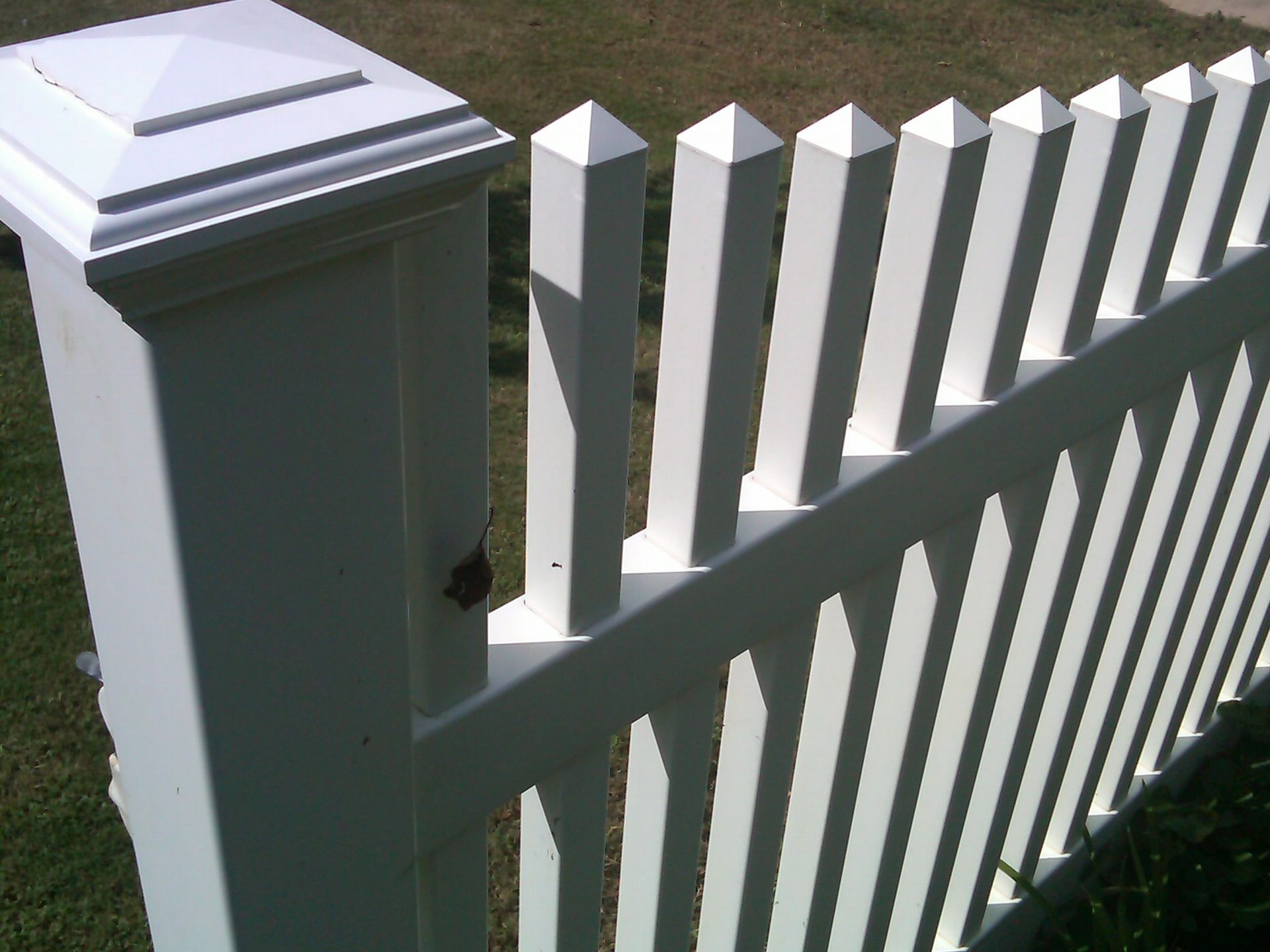 A white vinyl picket fence with a square post top