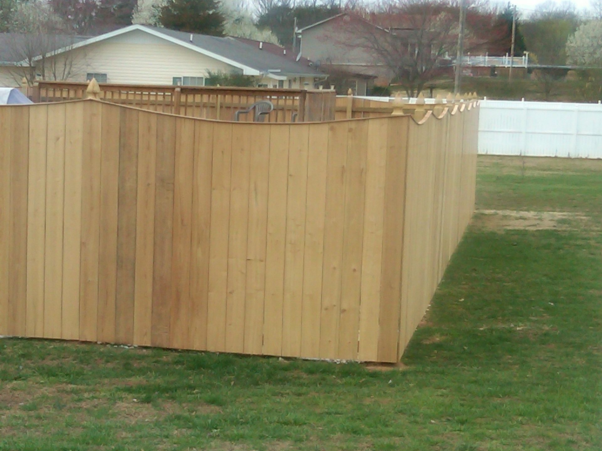 A wood privacy fence with a white fence in the background