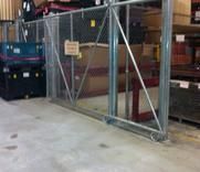 A warehouse with a sliding gate and a chain link fence surrounding it.