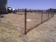 A warehouse with a sliding gate and a chain link fence surrounding it.
