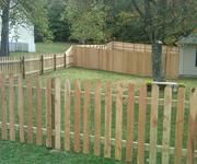 A wooden picket fence surrounds a lush green yard.