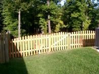 A wooden picket fence surrounds a lush green yard.
