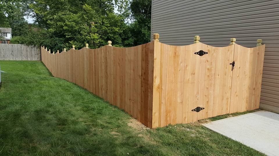 A wood privacy fence with a gate in the backyard of a house.