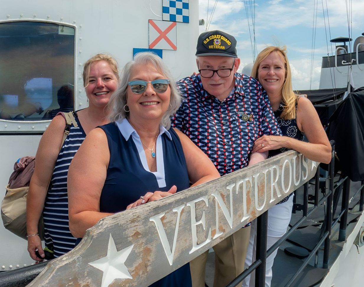 Four people, smiling, posing next to a sign reading 