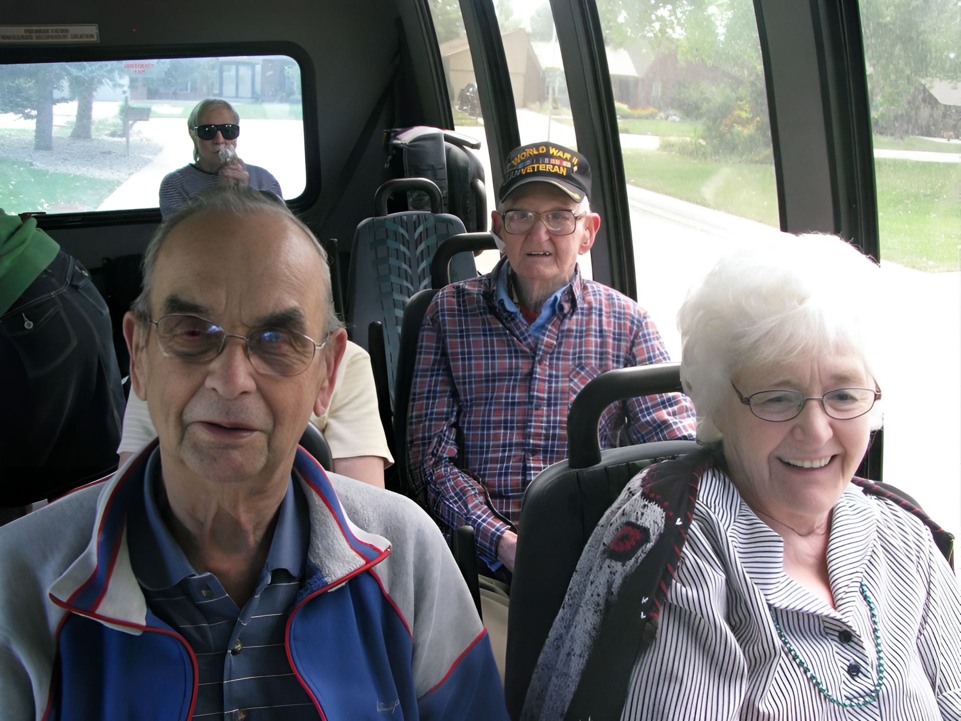 People on a bus. Elderly individuals seated, smiling. Others visible through window.