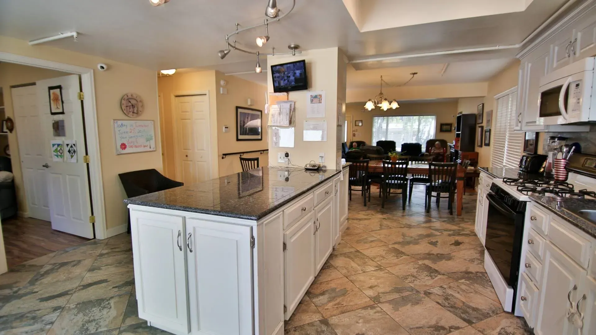 Kitchen with white cabinets, dark granite island, and dining area in the background.