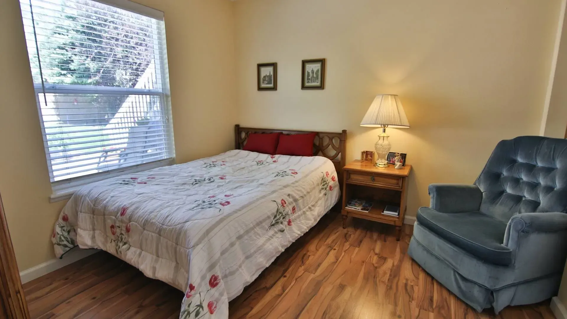 Small bedroom with a bed, nightstand, armchair, and window with natural light.