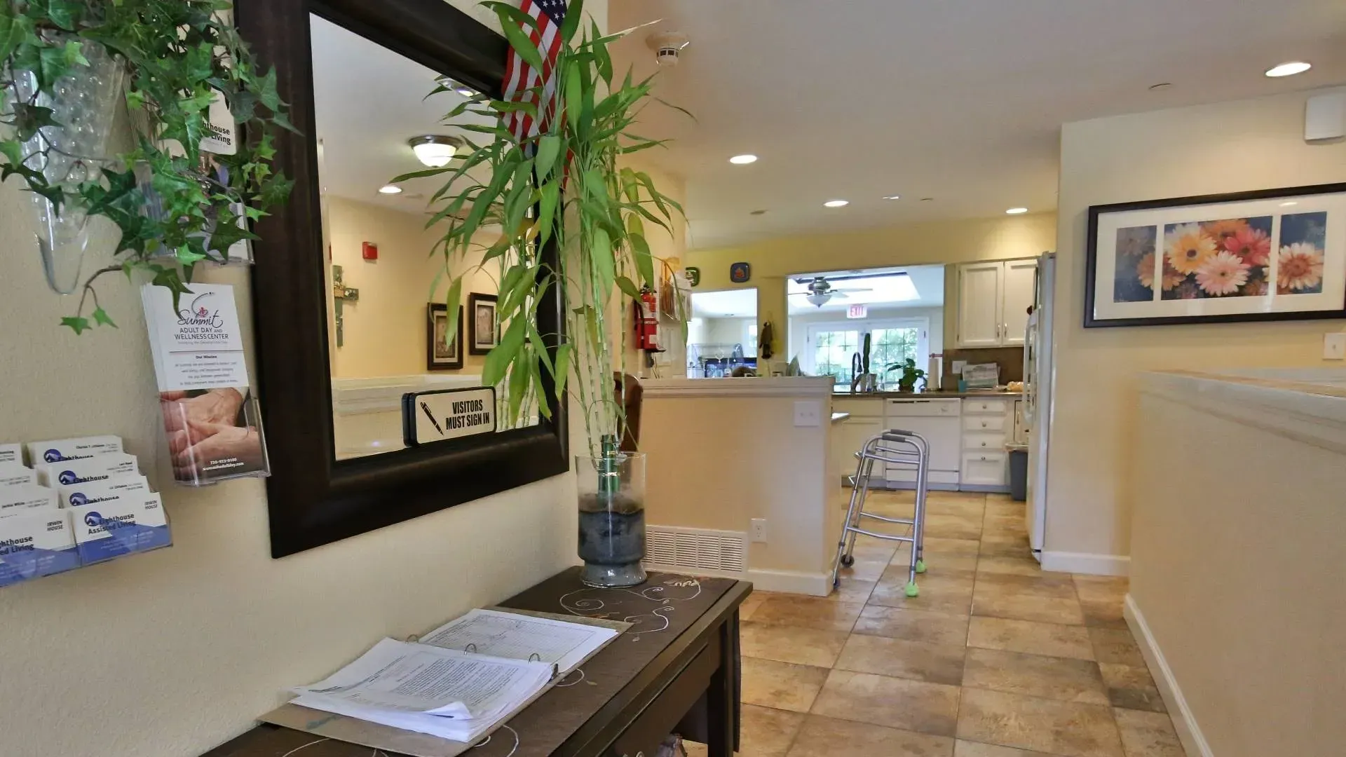 Hallway with a table, mirror, and a view into a kitchen.