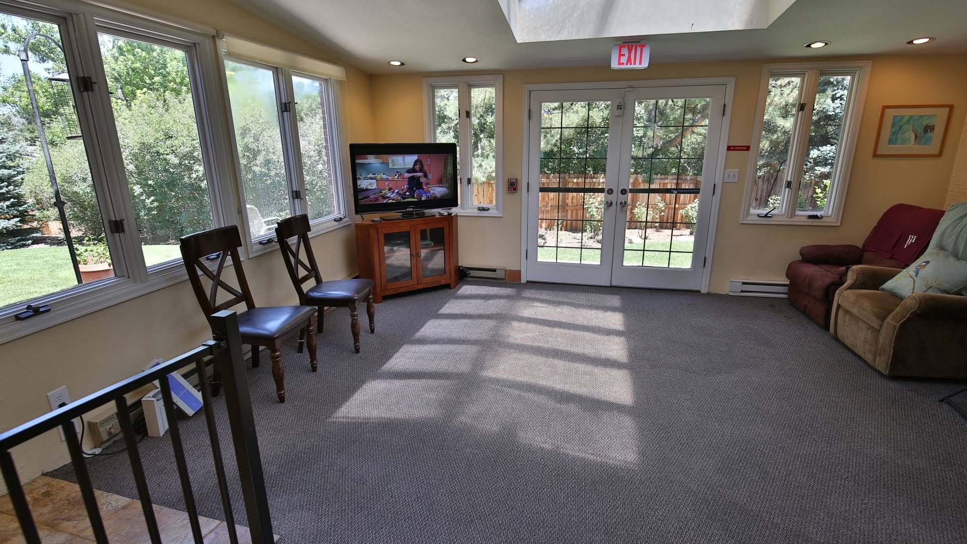 Sunroom with TV, chairs, and glass doors leading to the outdoors.