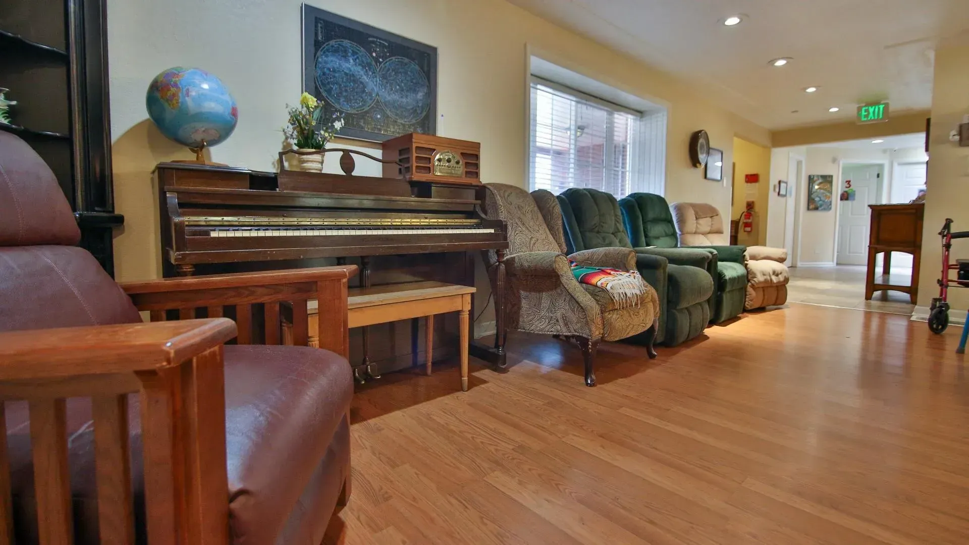 Living room with piano, chairs, globe, artwork, and a hallway.