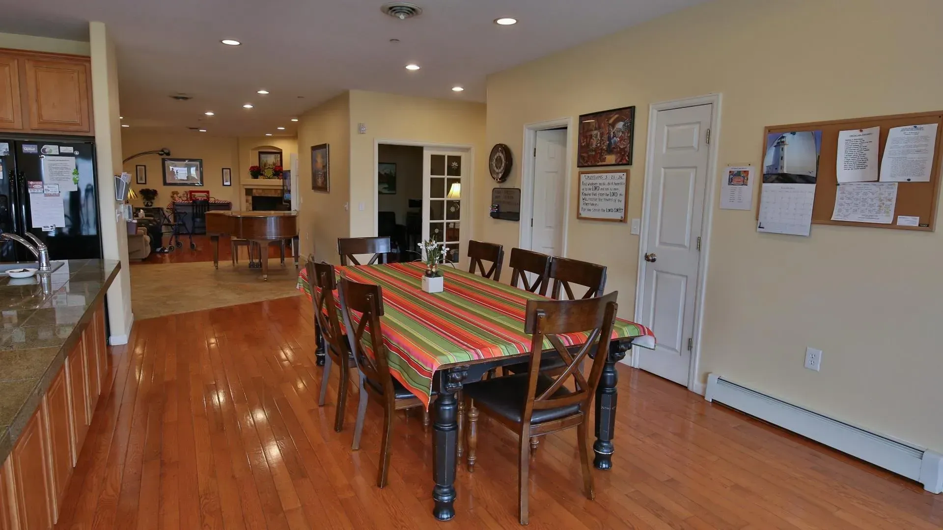 Open-concept dining area with a long table and chairs, hardwood floors, and access to other rooms.