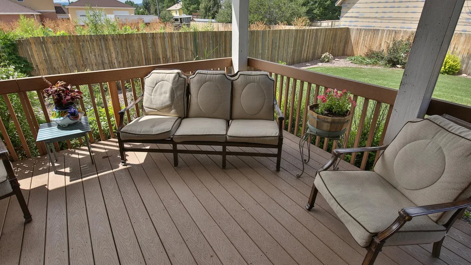 Wooden deck with outdoor seating, potted plants, and a bamboo fence.
