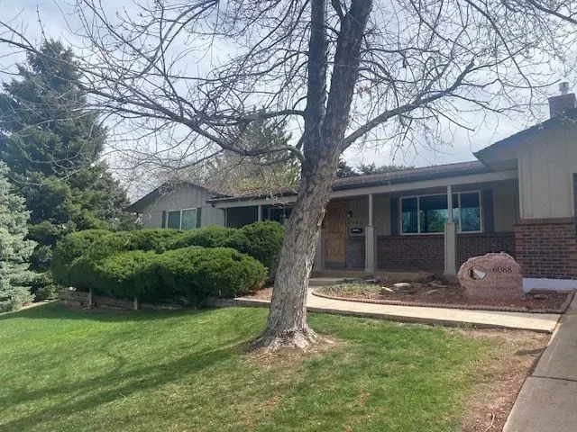 House with porch, tree in front. Green lawn, blue sky.