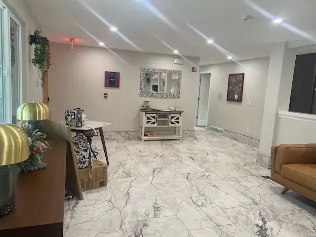 Bright lobby with marble floors, artwork, and a brown leather sofa.