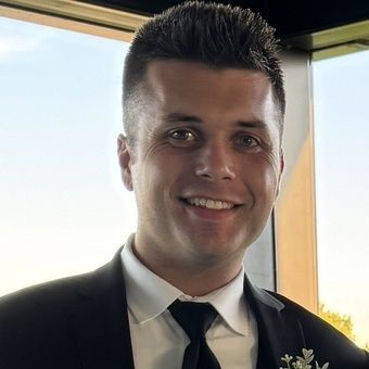 A man and a woman are sitting on a dock overlooking a lake.
