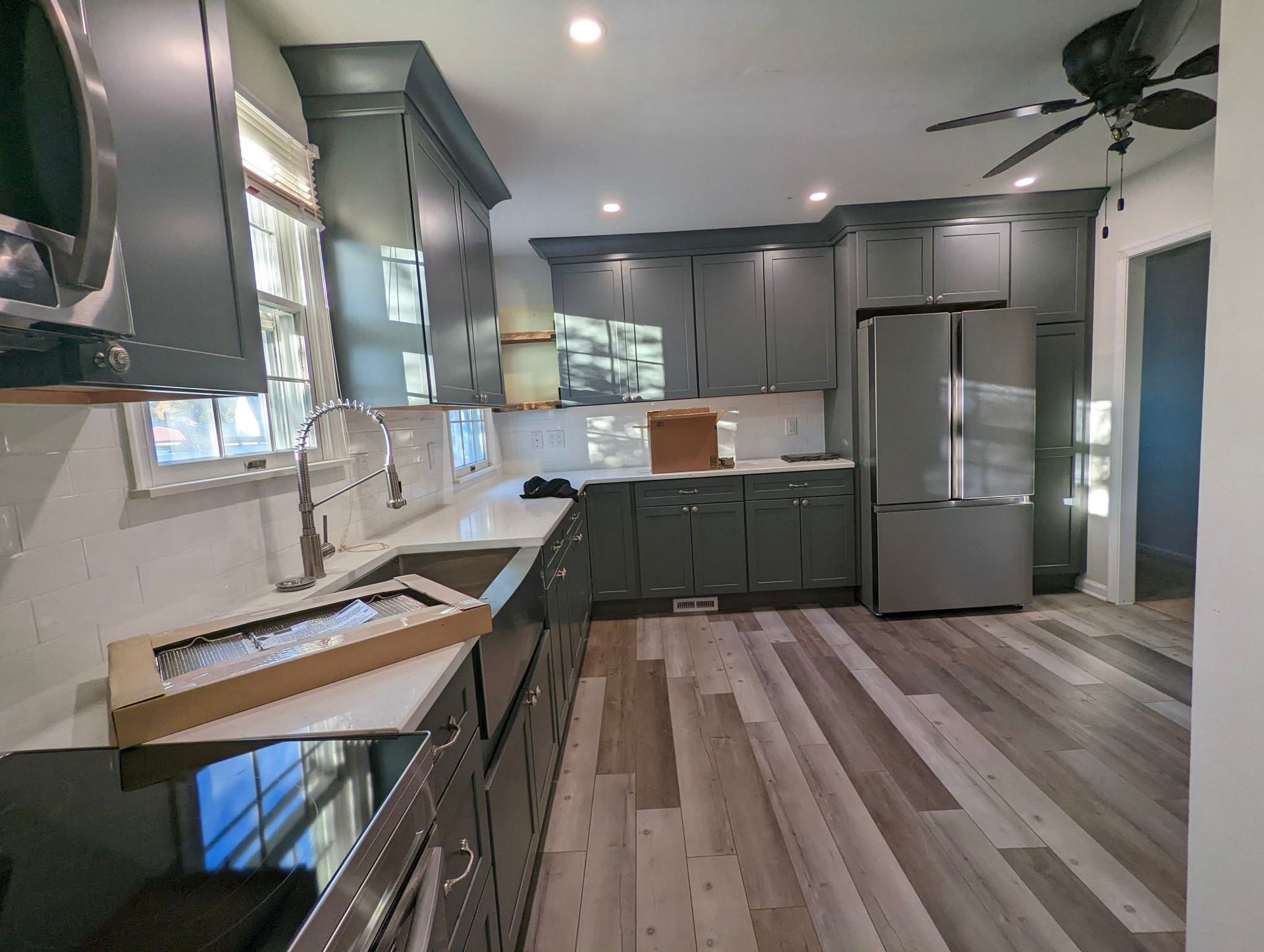 a kitchen with gray cabinets , stainless steel appliances , and a ceiling fan .