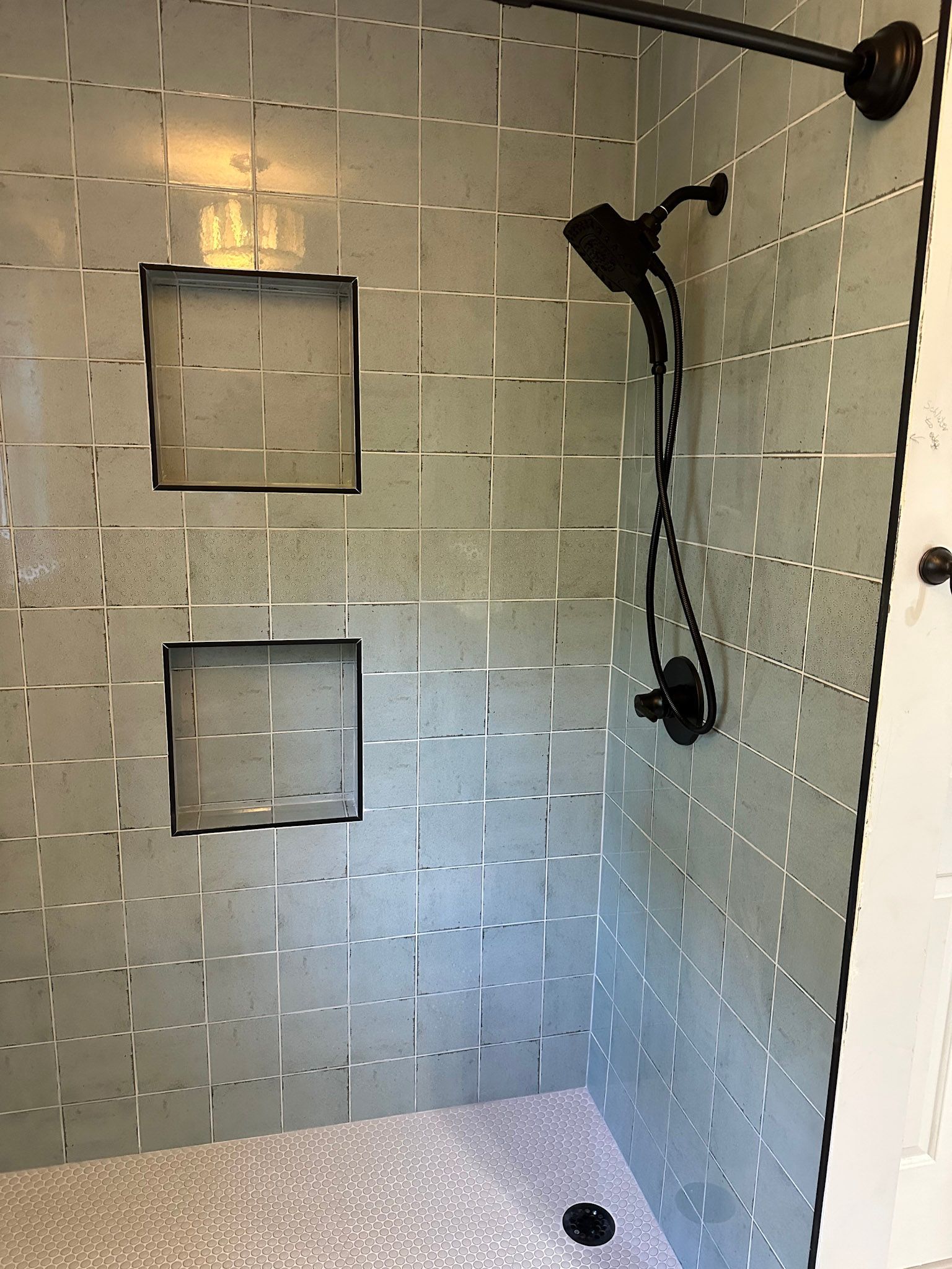 a shower with a shower head and two shelves on the wall .