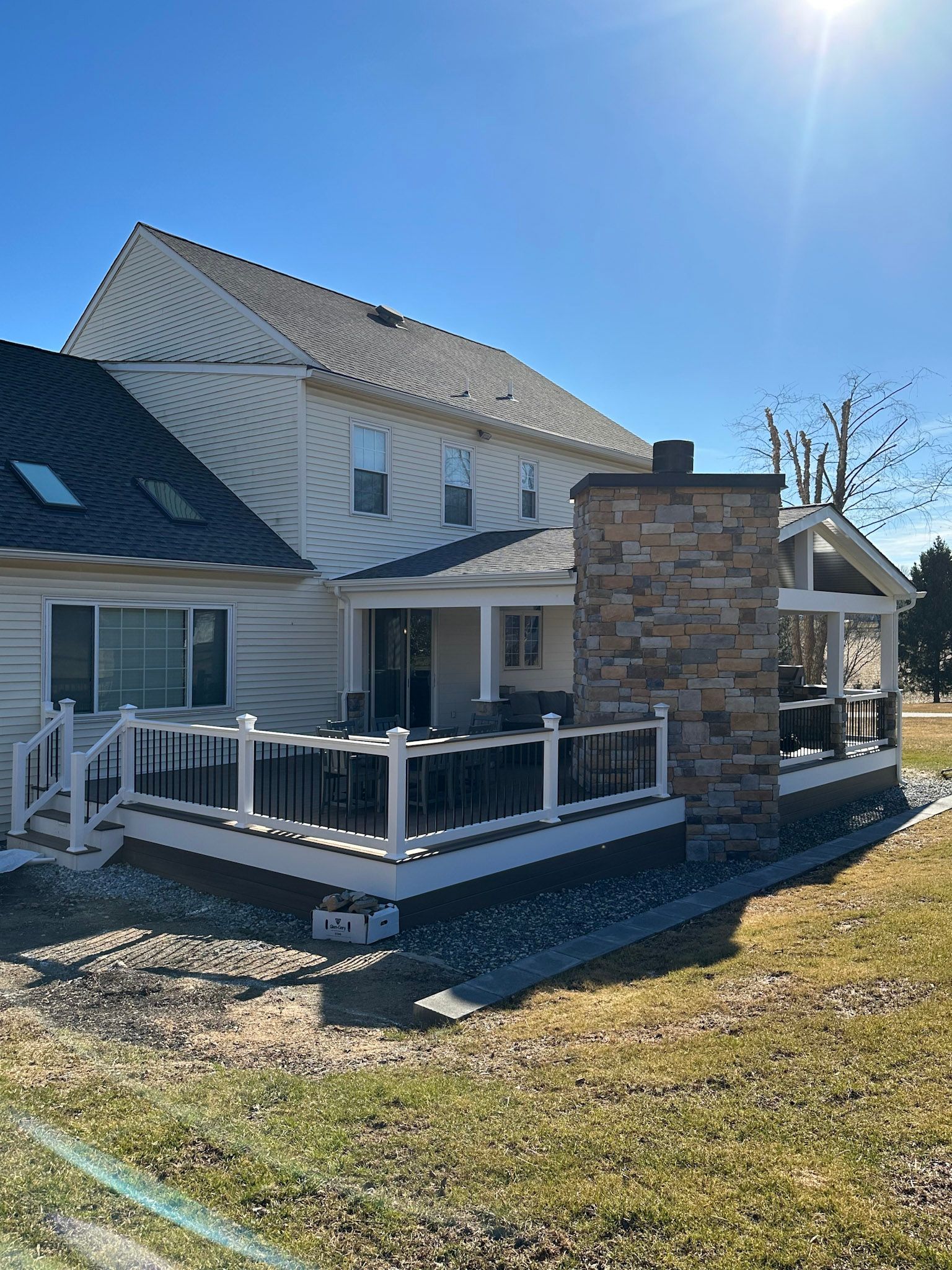 a white house with a large porch and a stone chimney .