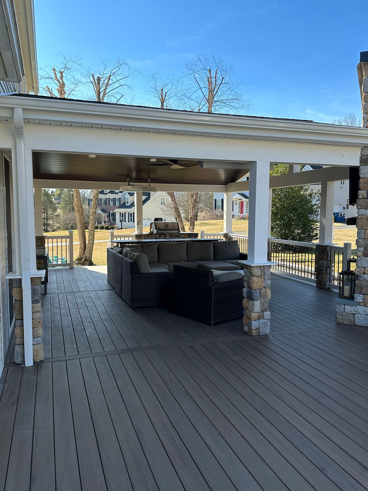 a wooden deck with a couch under a covered area