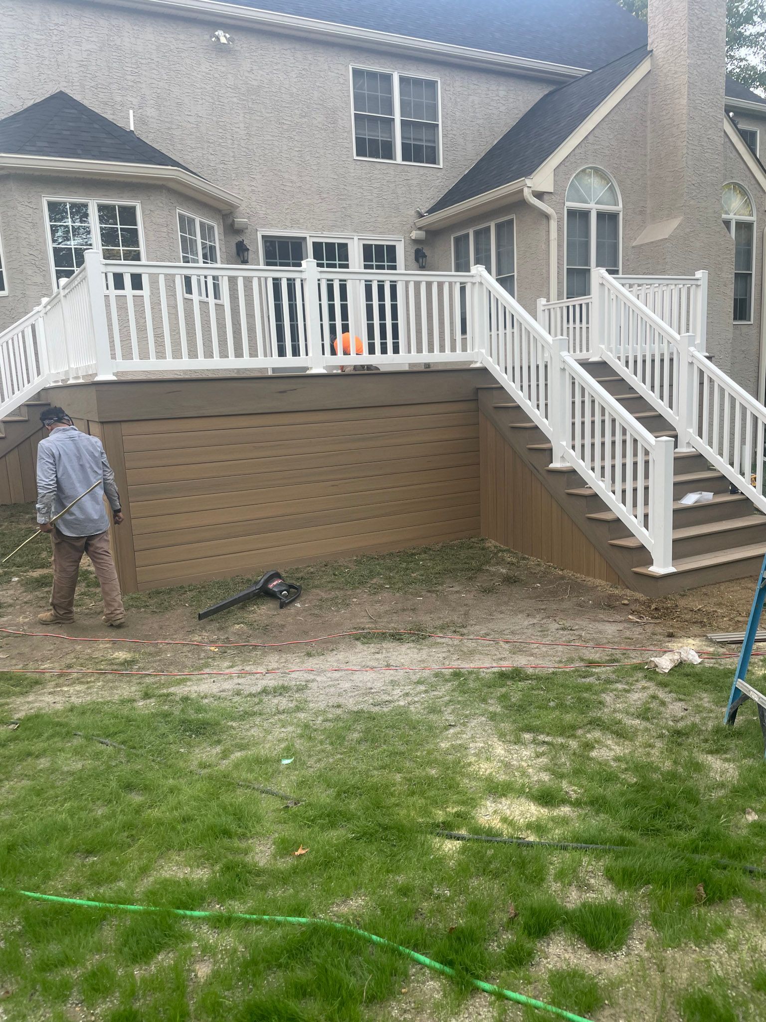 a man is standing in front of a house with a deck and stairs .