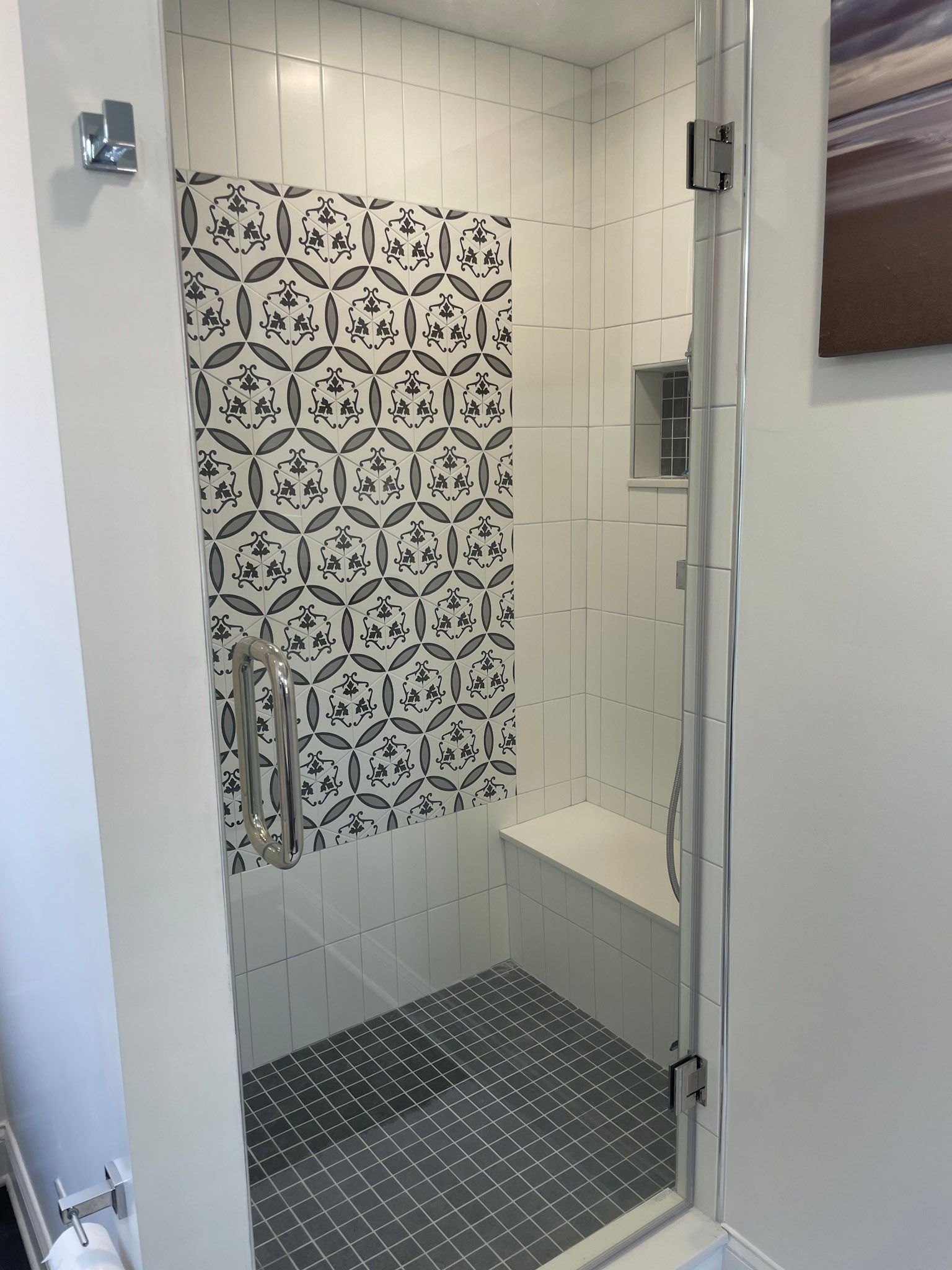 a bathroom with a walk in shower with a black and white tile wall .